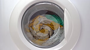 Washing machine with dirty clothes inside. Front view ashing things in the washing machine. Rtation of the drum of the