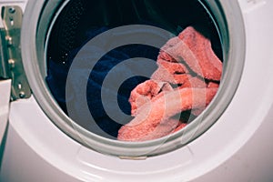 Washing machine door, clean colorful clothes, blue and pink towels