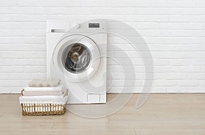 Washing machine and laundry basket on white brick wall background
