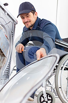 washing machine repairman in wheelchair dismantles machine