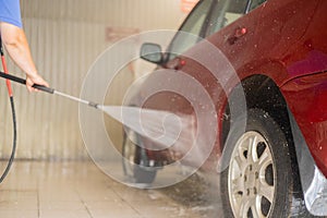 After washing, the man covers the car with protective wax. The driver washes the car after a long drive with foam and