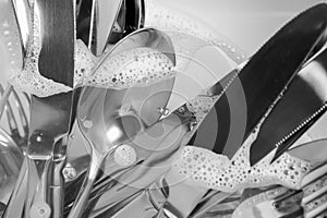 Washing silver spoons, forks and knives in kitchen sink with water, closeup