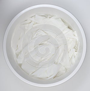 Washing white linen in a white plastic bowl