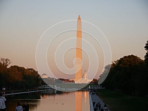 Washington Monument reflected on the pool with trees in the background at sunset