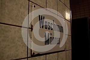 Washroom men sign on a tile-walled surface, closeup shot