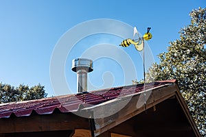 A wasp-shaped weather vane that moves with the wind on the roof of a wooden house.