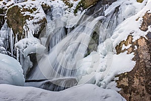 wasserfall mit felsen und schnee im gebirge