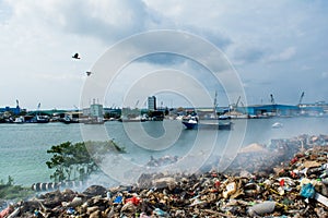 Wastage zone at the garbage dump full of smoke, litter, plastic bottles,rubbish and trash at tropical island