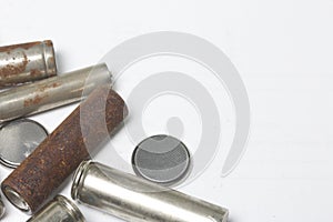 Waste batteries of different types are scattered. On a white background. View from above.