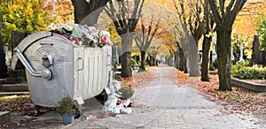 Waste bin among Trees in bright fall colors in the cemetery. Graves and golden maple leaves on All Souls Day,