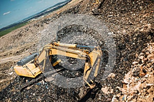 waste on dumping grounds. Details of industrial excavators working, digging and loading