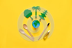 Less waste eco freindly flat lay. Green trees, Earth, wooden cutlery and toothbrush. no plastic