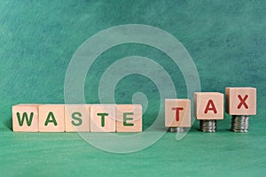 Waste or environmental tax concept. Word in wooden blocks with increasing stack of coins.