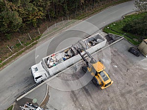Waste loading operation, loader dumping trash in a truck, drone shot