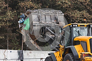 Waste loading operation, loader dumping trash in a truck