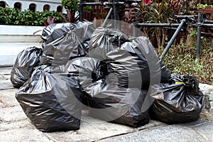 Waste lots pile of garbage black bags plastic stack on the floor ground public park, many dump black garbage plastic bags stack