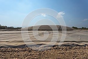 Waste of poultry farm to biogas. Worker laying thick sheet at the bottom of digester lagoon.