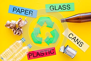 Waste for recycle and reuse near recycle symbol with arrows. Words paper, glass, plastic, cans on yellow background top