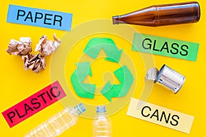 Waste for recycle and reuse near recycle symbol with arrows. Words paper, glass, plastic, cans on yellow background top