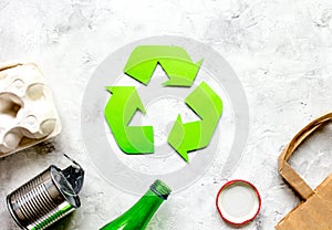 Waste recycling symbol with garbage on stone background top view mockup