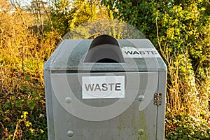 Waste sign on a silver steel trash can or bin in the countryside park