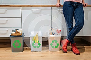 Waste sorting. Cropped view of colorful garbage bins filled with plastic, bio food, paper near womans legs in the