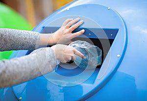 Waste Sorting. Hand throwing plastic bag into blue recycle bin outdoors
