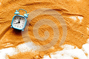 Waste of time concept. Clock on sand on white background top-down