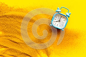 Waste of time concept. Clock on sand on yellow background top-down
