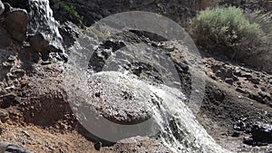 Waste water flows out of a sewage pipe into a sandy hole