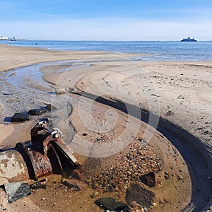 Waste water pipe with valve at sand beach at low tide