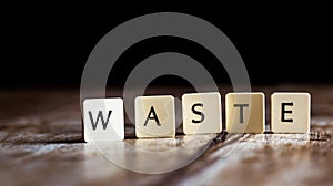 Waste word made of tiles on dark wooden background