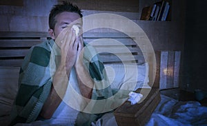 Wasted man sick at home freezing in bed covered with blanket sniffing sneezing and blowing nose suffering grippe feeling unwell photo