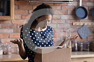 Irritated latin woman receive broken damaged goods in delivery box photo