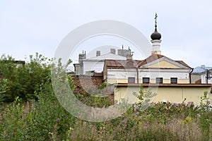 A wasteland overgrown with grass, a brick wall and an old church in Rybinsk, Russia