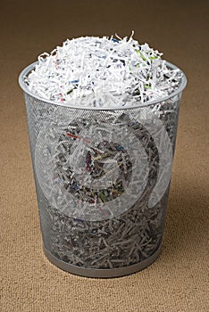 Wastepaper basket filled with shredded paper photo