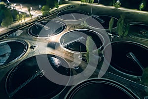 Wastewater Treatment Plant with tanks for purification and filtration of urban waste water, aerial view at night