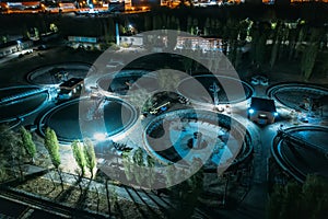 Wastewater Treatment Plant with tanks for purification and filtration of urban waste water, aerial view at night