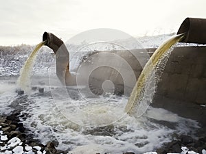 Wastewater from two large rusty pipes merge into the river