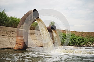 Wastewater from two large rusty pipes merge into the river
