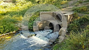 Wastewater from two large rusty pipes merge into the river