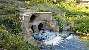 Wastewater from two large rusty pipes merge into the river