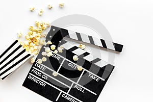 Watch film in cinema with popcorn and clapperboard on white background top view