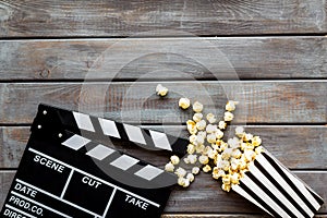 Watch film in cinema with popcorn and clapperboard on wooden background top view