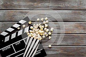 Watch film in cinema with popcorn and clapperboard on wooden background top view