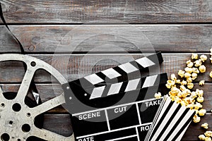 Watch film in cinema with popcorn, video tape and clapperboard on wooden background top view