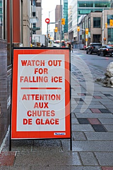 Watch out of falling snow and ice sign on the sidewalk warning of the danger