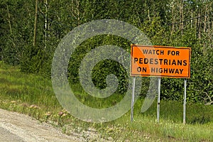 Watch for pedestrians on roadway sign beside a road