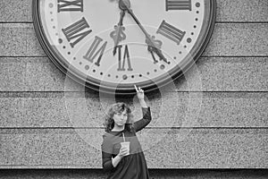 Watch the time concept woman in dark red dress next to huge watch over her head