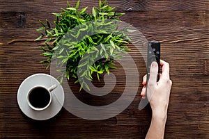 Watch TV concept. TV remote in hand on dark wooden background top-down